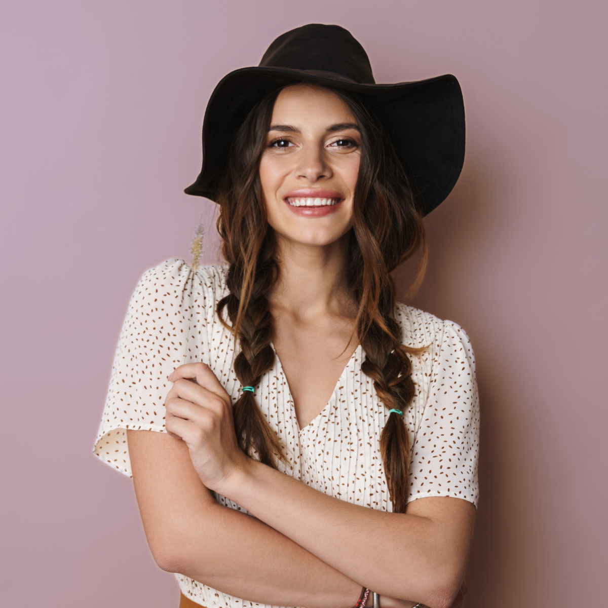 A young woman smiling and wearing a black fashion hat.